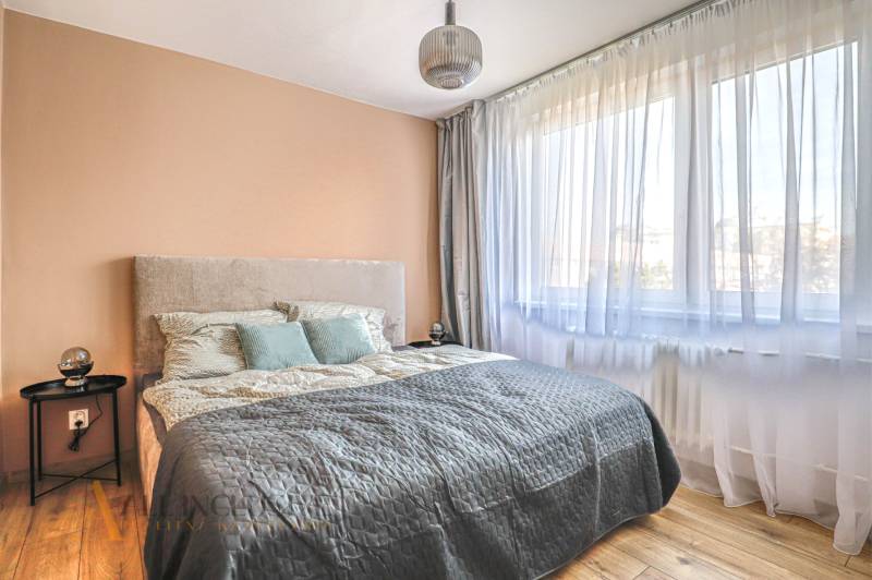 Schlafzimmer mit Bett, Vorhängen und Hängelampe in einer 3-Zimmer-Wohnung.