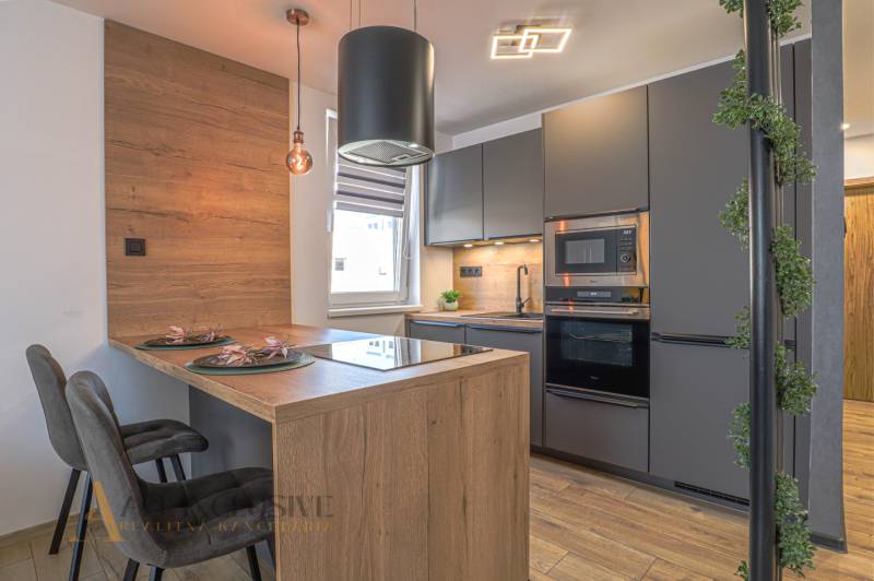 Küche in einer 3-Zimmer-Wohnung mit Holzelementen, modernen Geräten und einer Essbar.