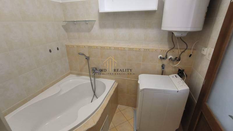 Badezimmer in einer 2-Zimmer-Wohnung mit Badewanne, Boiler und Waschmaschine.