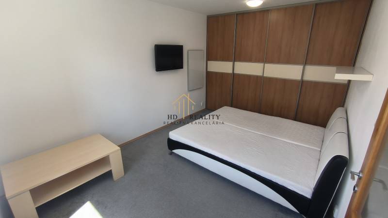 Schlafzimmer mit Doppelbett, Fernseher und Einbauschrank in einer 2-Zimmer-Wohnung.