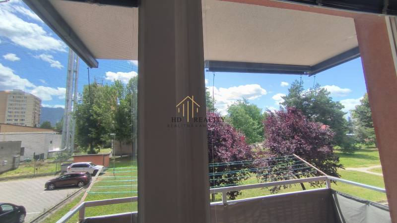 Blick vom Balkon in einer 2-Zimmer-Wohnung in Liptovský Mikuláš, Bäume und geparkte Autos.