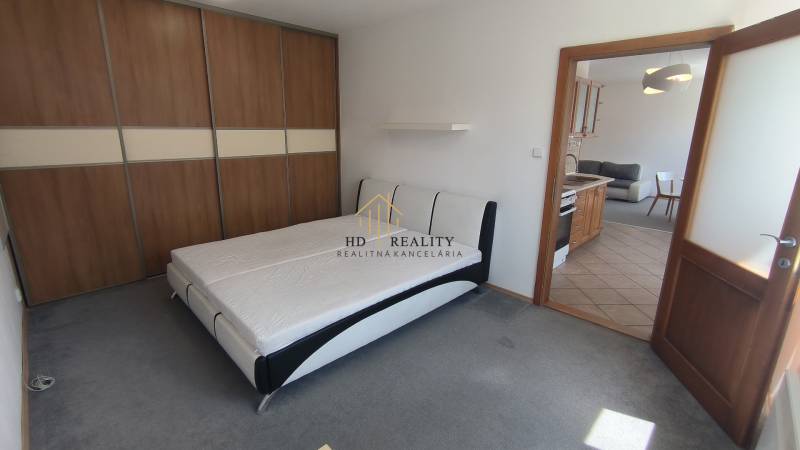 Schlafzimmer mit großem Schrank und Doppelbett, daneben Wohnzimmer mit Küchenzeile.