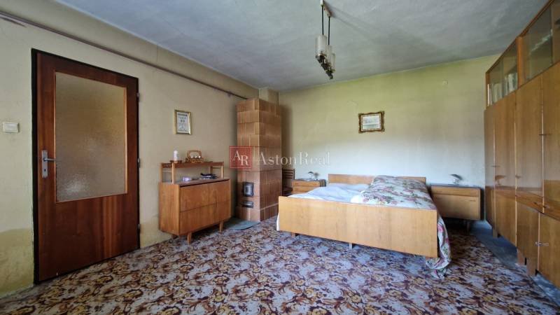 Ein Schlafzimmer in einem Einfamilienhaus mit antiken Möbeln und einem Kachelofen.