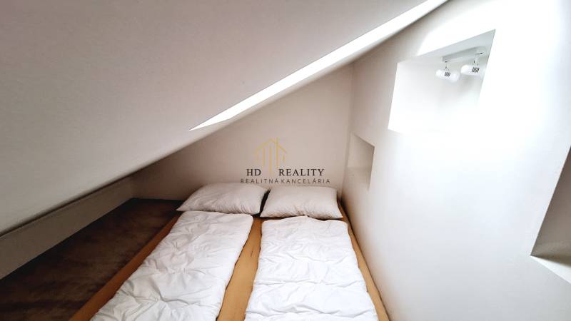 Dachbodenschlafzimmer mit einem Einzelbett und Dachfenster in einer 3-Zimmer-Wohnung.
