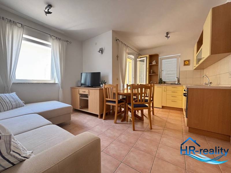 Obývačka in einer 2-Zimmer-Wohnung mit Küchenzeile, Sofa und Esstisch.