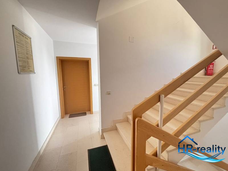 Flur mit Treppe und Holzgeländer in einer 2-Zimmer-Wohnung.