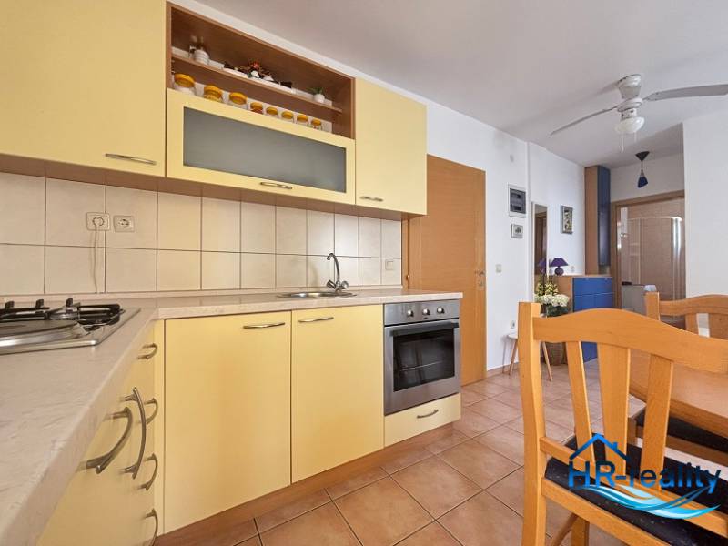 Küche in einer 2-Zimmer-Wohnung mit Holzmöbeln und eingebauten Geräten.