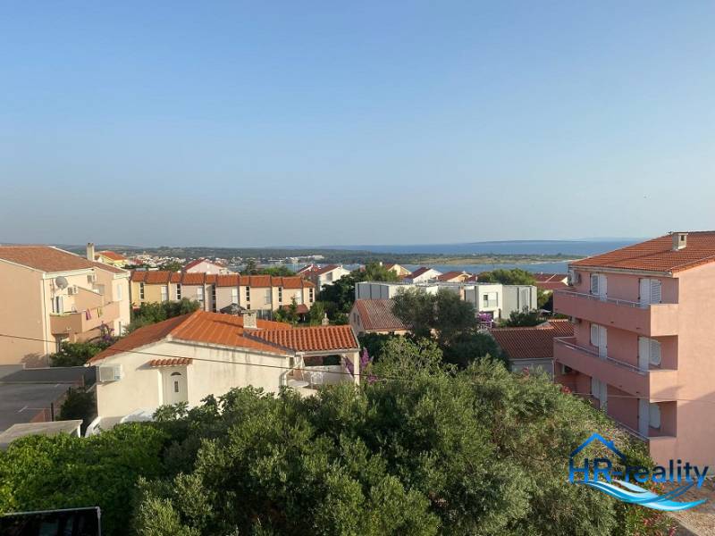 Blick aus einer 2-Zimmer-Wohnung in Novalja auf das Meer und die umliegenden Dächer.