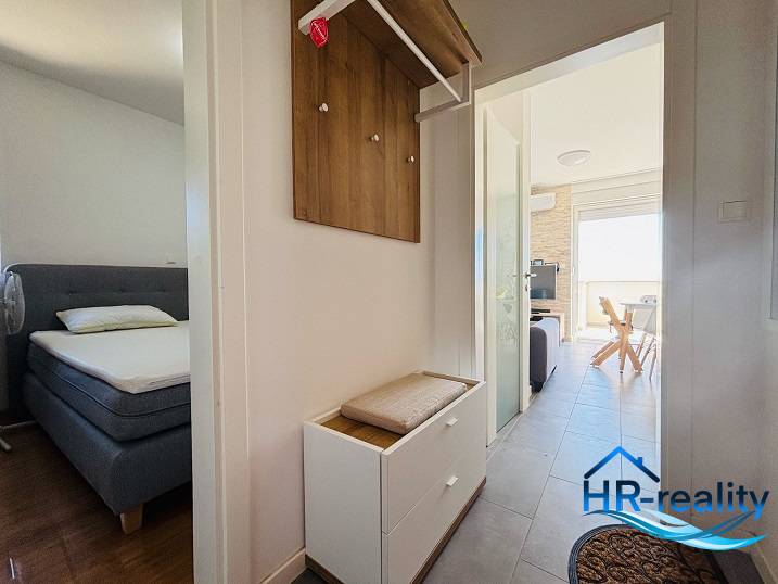 Der Flur, der zum Schlafzimmer und Wohnzimmer in einer 2-Zimmer-Wohnung mit hellen Möbeln führt.