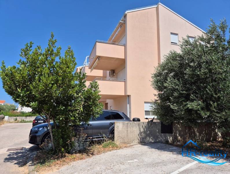 Ein Gebäude mit einem Parkplatz und Bäumen in der Nähe einer 2-Zimmer-Wohnung in Novalja.