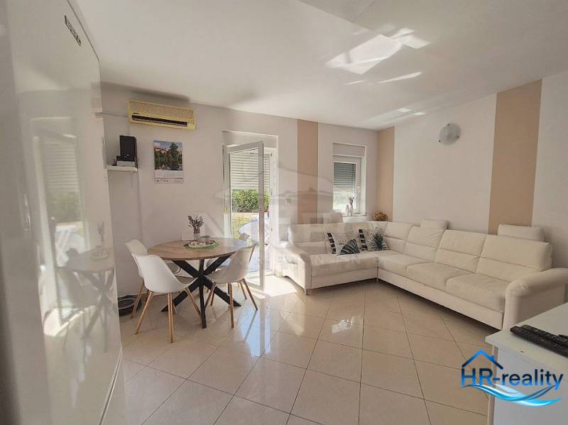 Wohnzimmer in einer Zweizimmerwohnung mit weißem Sofa und Esstisch.