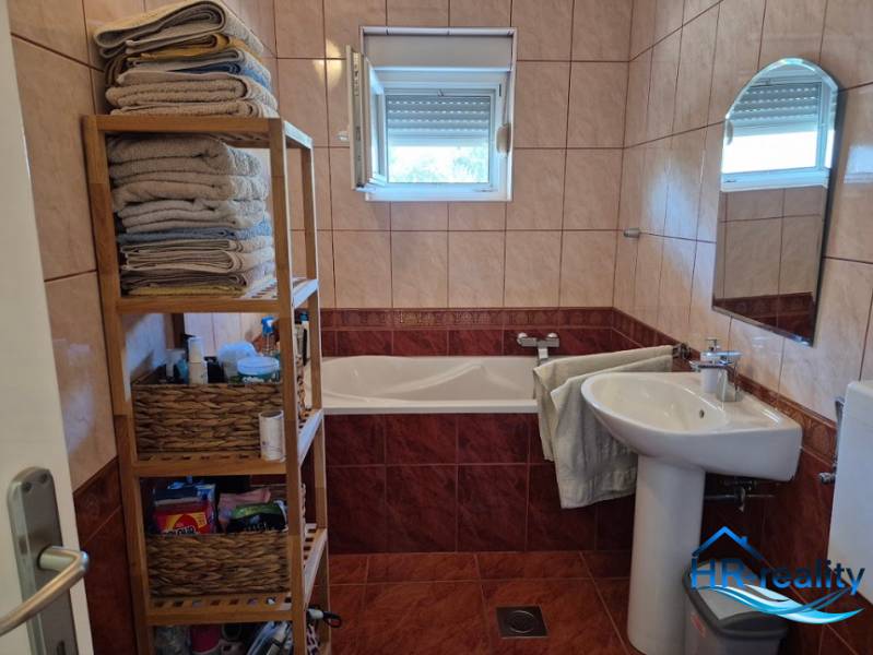 Badezimmer in einer 2-Zimmer-Wohnung mit Badewanne, Regalen und Fenster.