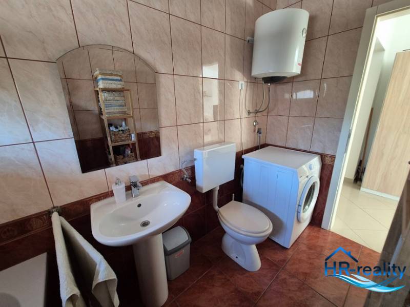 Badezimmer mit Spiegel, Waschbecken, Waschmaschine und Toilette in einer 2-Zimmer-Wohnung.