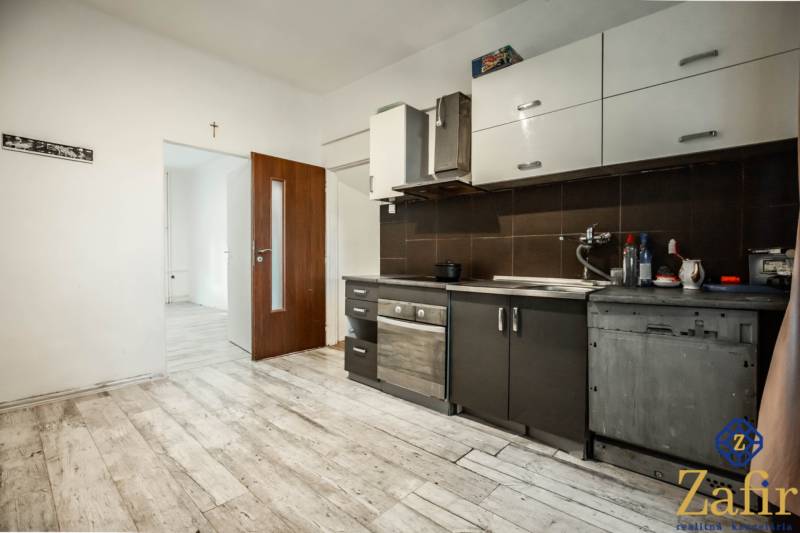 Küche in einer 3-Zimmer-Wohnung mit Holzboden und dunklen Schränken.