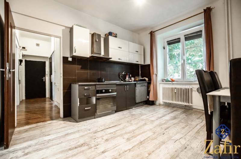Küche in einer 3-Zimmer-Wohnung mit weißen Möbeln und dunklen Fliesen, heller Raum.