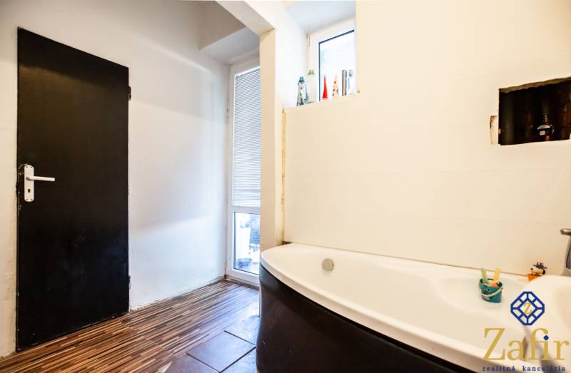 Badezimmer mit Badewanne in einer 3-Zimmer-Wohnung. Weiße Wände, Türen und Holzboden.