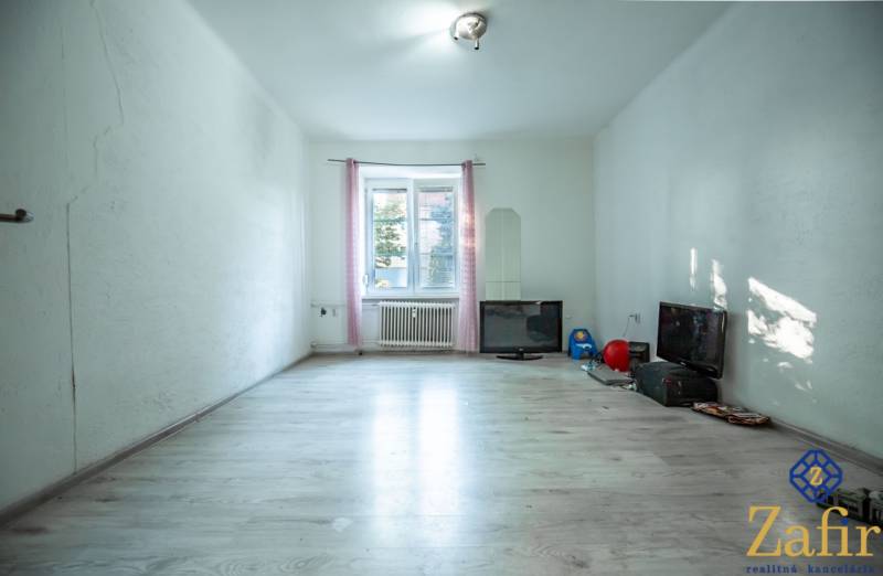Ein geräumiges Zimmer in einer 3-Zimmer-Wohnung mit Laminatboden und Fernseher.