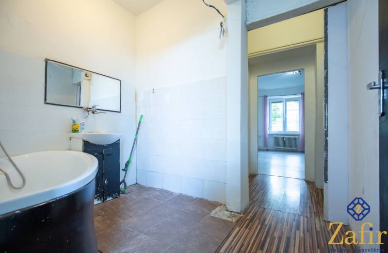 Badezimmer in einer 3-Zimmer-Wohnung mit Spiegel, Badewanne und Ausgang in den Raum.