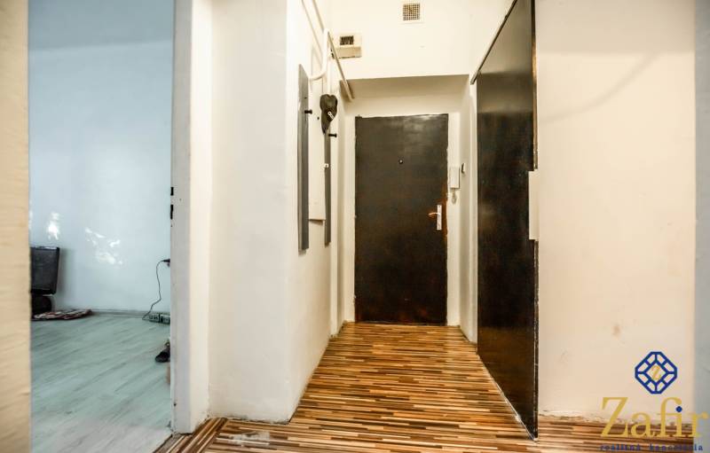 Flur einer 3-Zimmer-Wohnung mit Holzboden und Eingangstür.