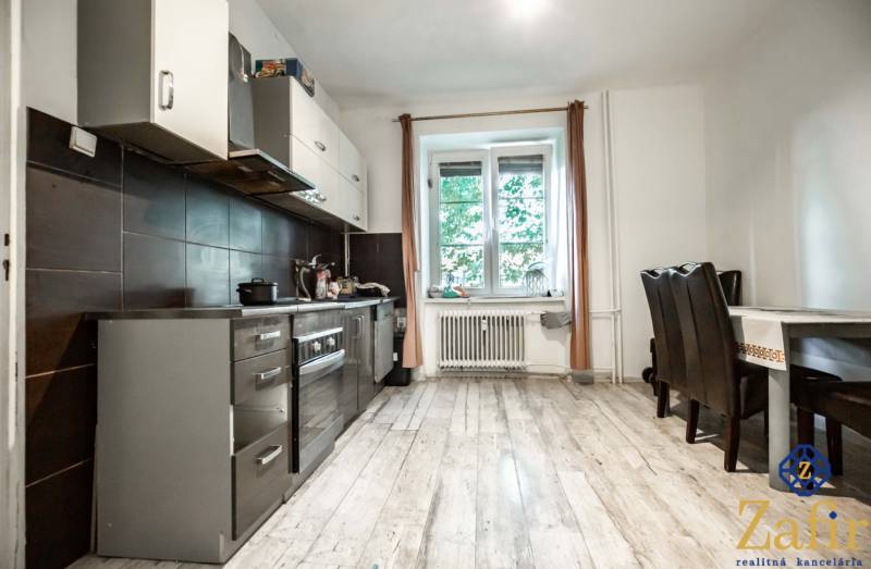 Die Küche in der 3-Zimmer-Wohnung mit dunklen Möbeln und einem Esstisch am Fenster.