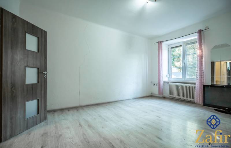 Ein heller Raum mit Holzboden und einem Fenster in einer 3-Zimmer-Wohnung.