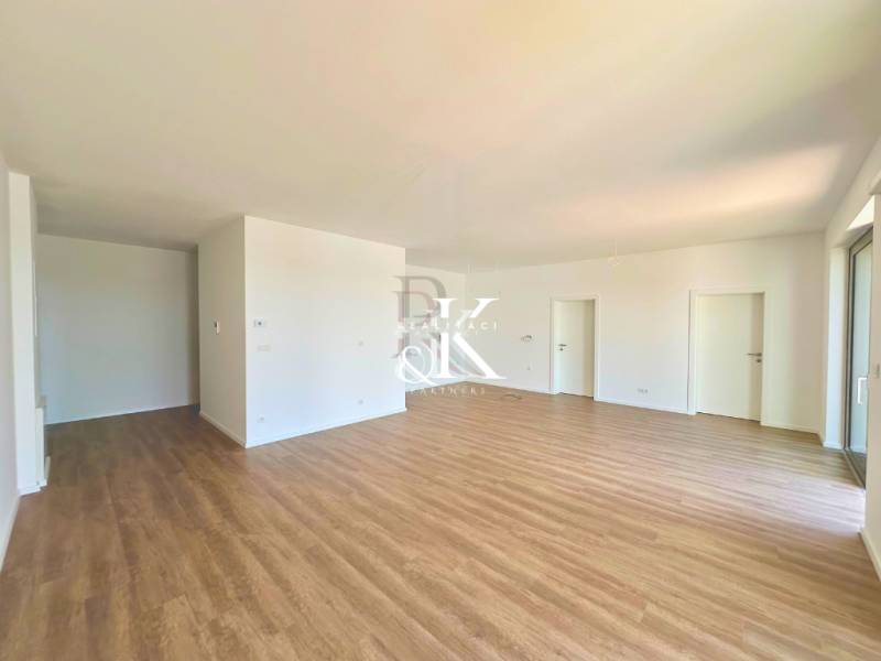 Geräumiges Zimmer mit Holzboden und weißen Wänden in einer 3-Zimmer-Wohnung.