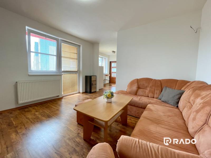 Wohnzimmer in einer Zweizimmerwohnung mit einem orangefarbenen Sofa und einem Holztisch.