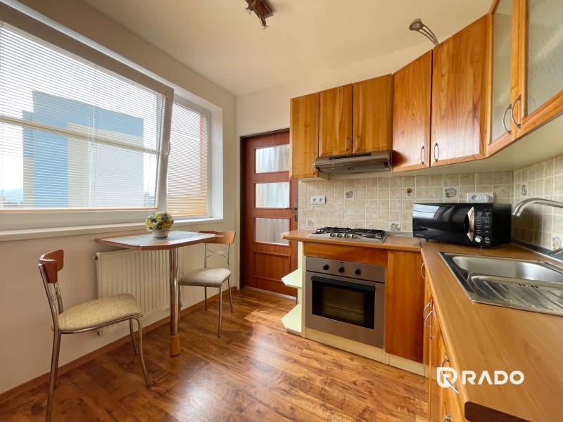 Küche in einer 2-Zimmer-Wohnung mit Holzküche und Tisch am Fenster.