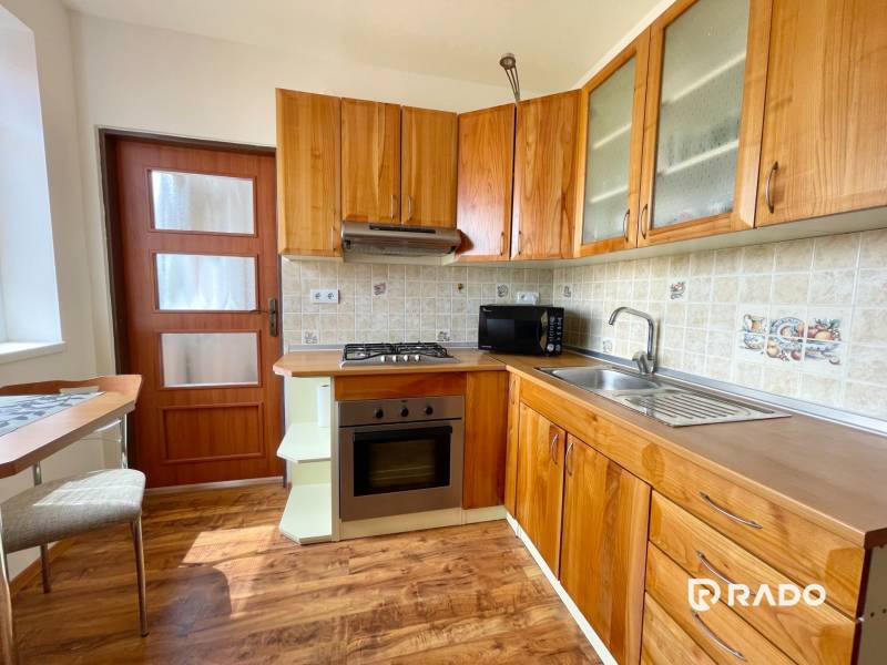 Küche in einer 2-Zimmer-Wohnung mit Holzschränken und Geräten.