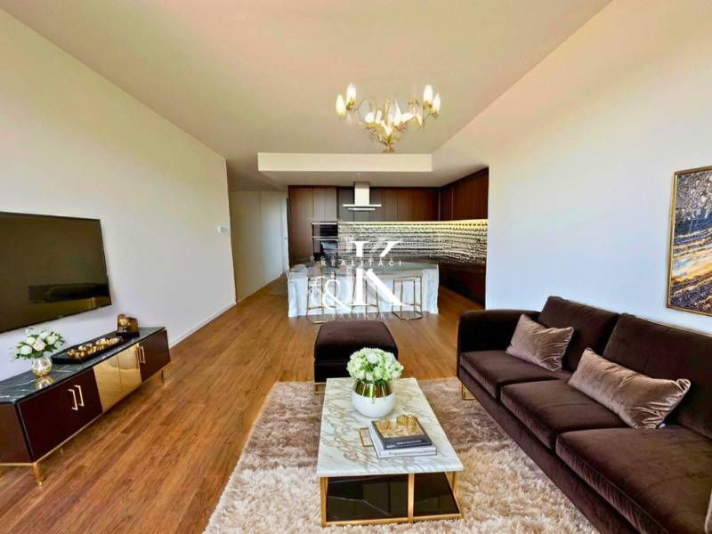 Wohnzimmer in einer Zweizimmerwohnung mit Sofa, Fernseher und Essecke.