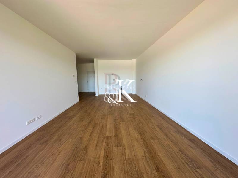 Ein geräumiges Zimmer in einer 2-Zimmer-Wohnung mit Holzboden und weißen Wänden.