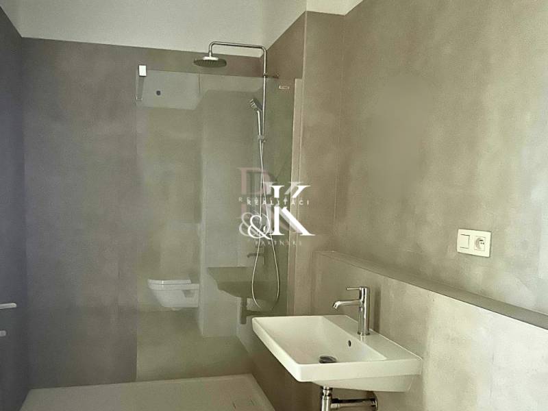 Ein stilvolles Badezimmer mit einer eleganten Duschkabine und einem Waschbecken in einer 2-Zimmer-Wohnung.