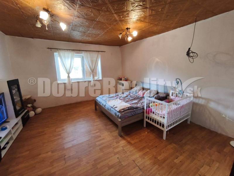 Schlafzimmer im Einfamilienhaus mit Bett, Kinderbett und Holzboden.