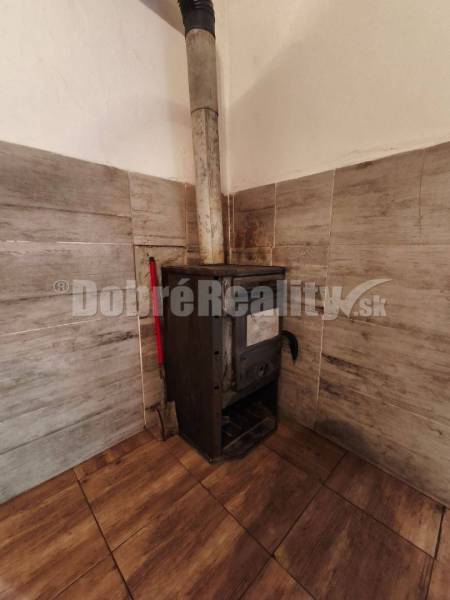 Ein Kamin in der Ecke eines Wohnzimmers in einem Einfamilienhaus mit Holzverkleidungen und Fliesen.