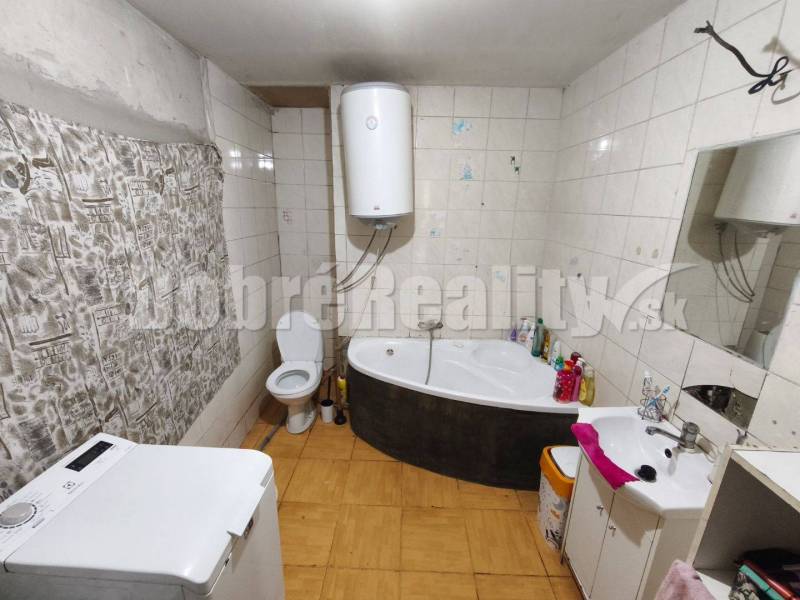 Badezimmer mit Badewanne, Waschmaschine, Toilette und Boiler im Einfamilienhaus.