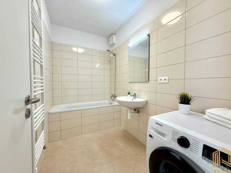 Badezimmer mit Badewanne, Waschbecken, Waschmaschine und Heizkörper in einer 2-Zimmer-Wohnung.