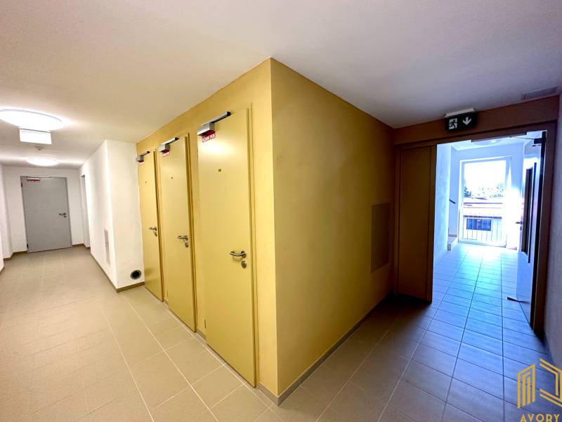 Ein Flur mit mehreren Türen in einer 2-Zimmer-Wohnung, helle Fliesen und ein Notausgang.