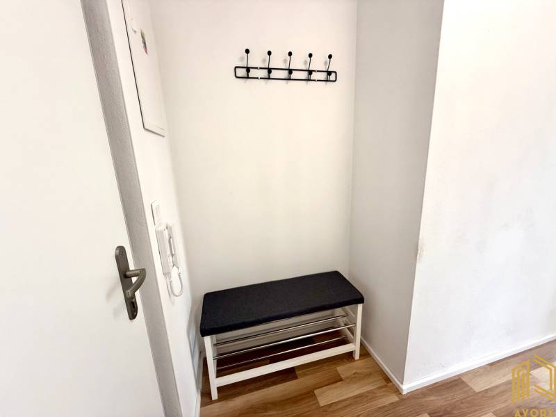 Eingangsflur in einer 2-Zimmer-Wohnung mit Bank und Wandgarderobe.