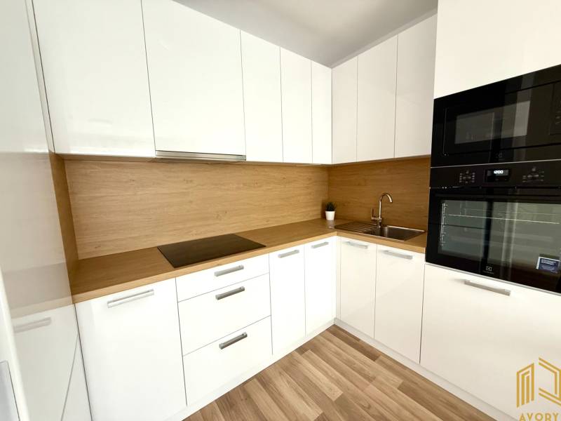 Küche in einer 2-Zimmer-Wohnung mit weißen Schränken und einer Holzarbeitsplatte.