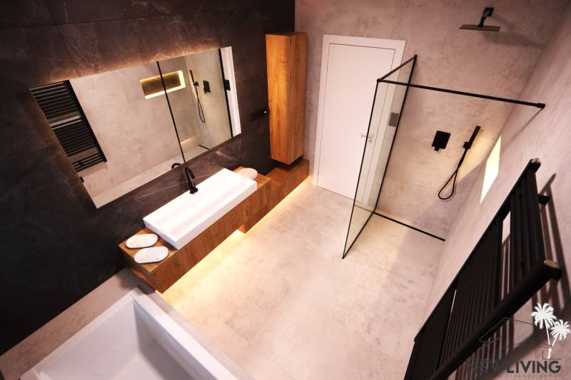Ein Badezimmer mit Holzmöbeln, einer Duschkabine und einer dunklen Wand in einem Einfamilienhaus.