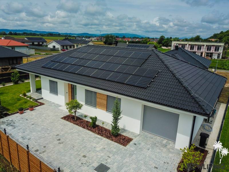 Ein Einfamilienhaus in Piešťany mit Photovoltaikmodulen auf dem Dach ist von einem grünen Garten umgeben.