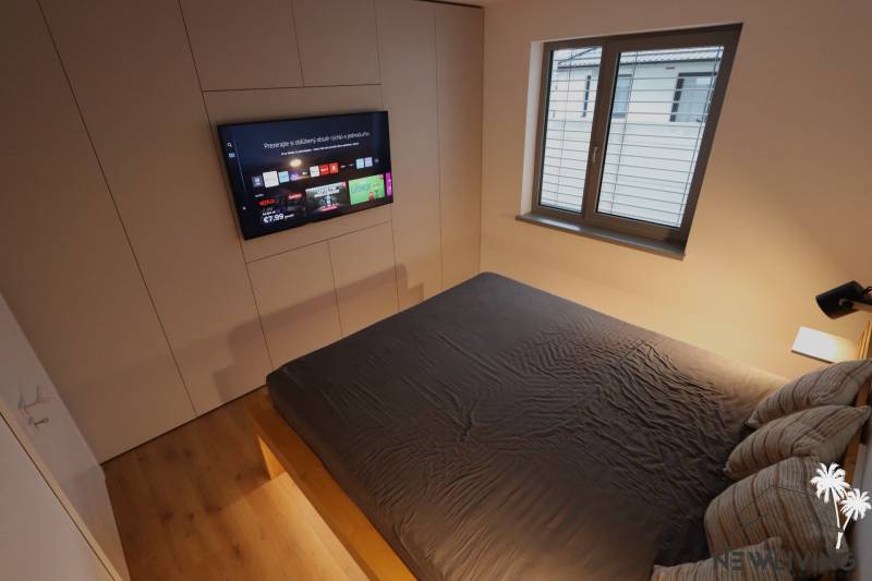 Schlafzimmer im Einfamilienhaus mit Fernseher, großem Bett und Fenster.