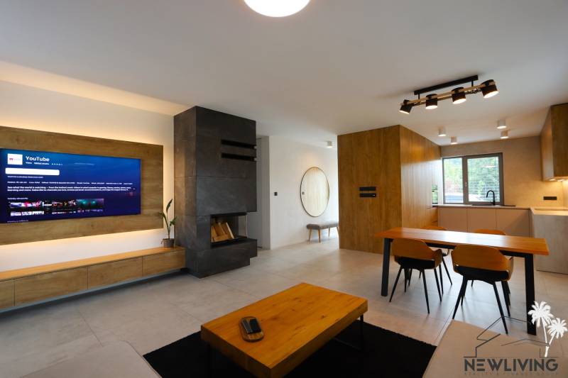 Wohnzimmer in einem Einfamilienhaus mit Kamin, Fernseher und Essecke.