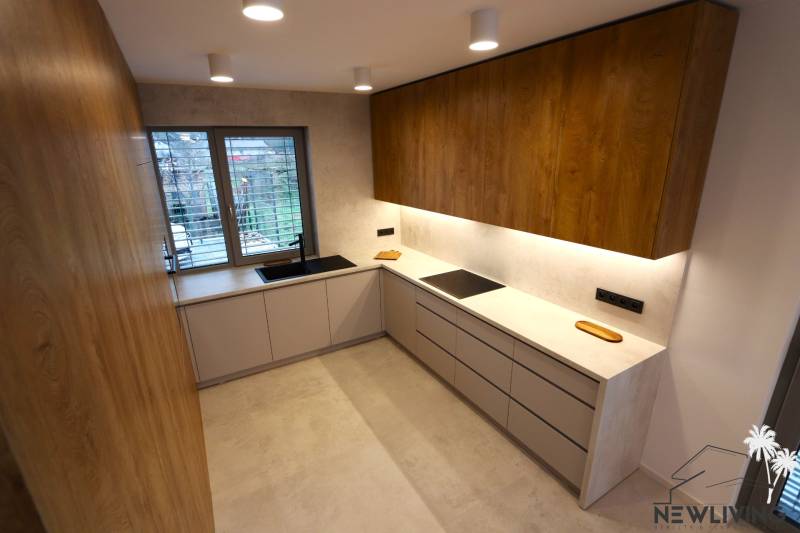Küche mit einem Holzschrank, einem Fenster und grauen Schränken in einem Einfamilienhaus.