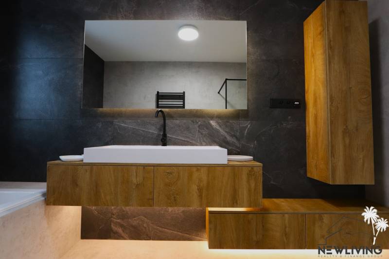 Badezimmer mit Waschbecken und Holzschrank in einem Einfamilienhaus.
