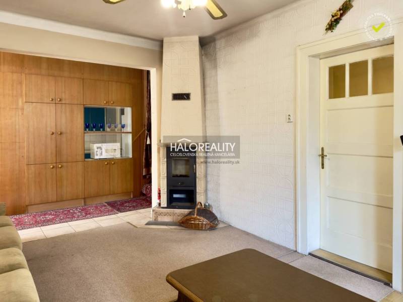 Wohnzimmer in einem Einfamilienhaus mit Kachelofen und Holzwand als Stauraum.