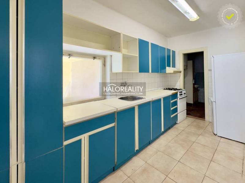 Küche in einem Einfamilienhaus mit blauen Schränken und weißen Geräten.