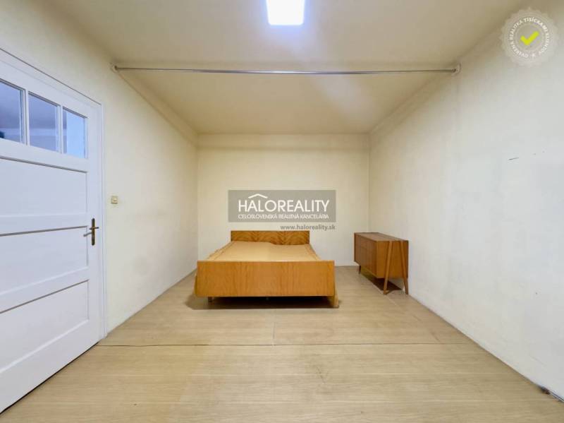 Schlafzimmer in einem Einfamilienhaus mit einem Holzbett und einer Kommode, helle Wände und Boden.