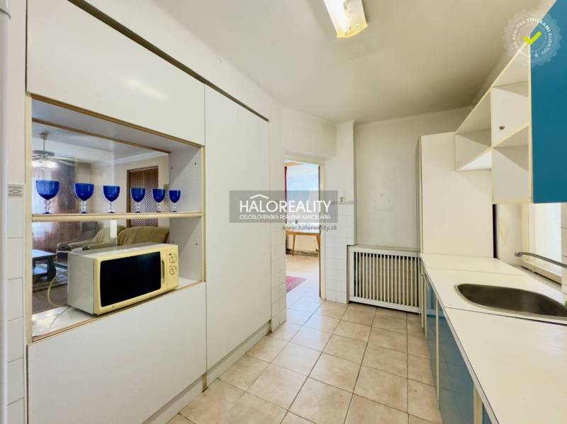 Eine Küche in einem Einfamilienhaus mit Dunstabzugshaube, Mikrowelle und blauen Gläsern auf dem Regal.