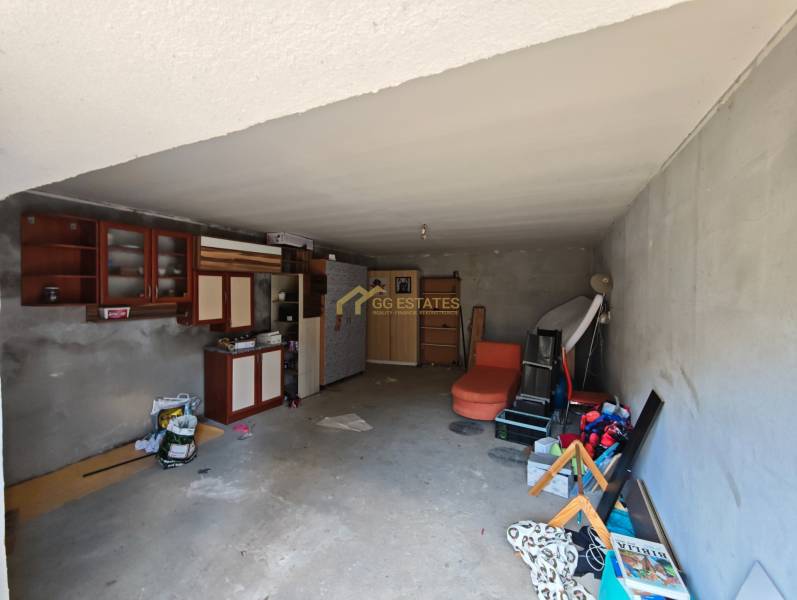 Innenraum einer Garage in einem Einfamilienhaus mit Regalen, Schränken und verschiedenen gelagerten Ausrüstungen.